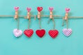 ValentineÃ¢â¬â¢s Day. Sewed pillow hearts row border on red, pink and white clothespins at rustic blue pastel wall. Royalty Free Stock Photo